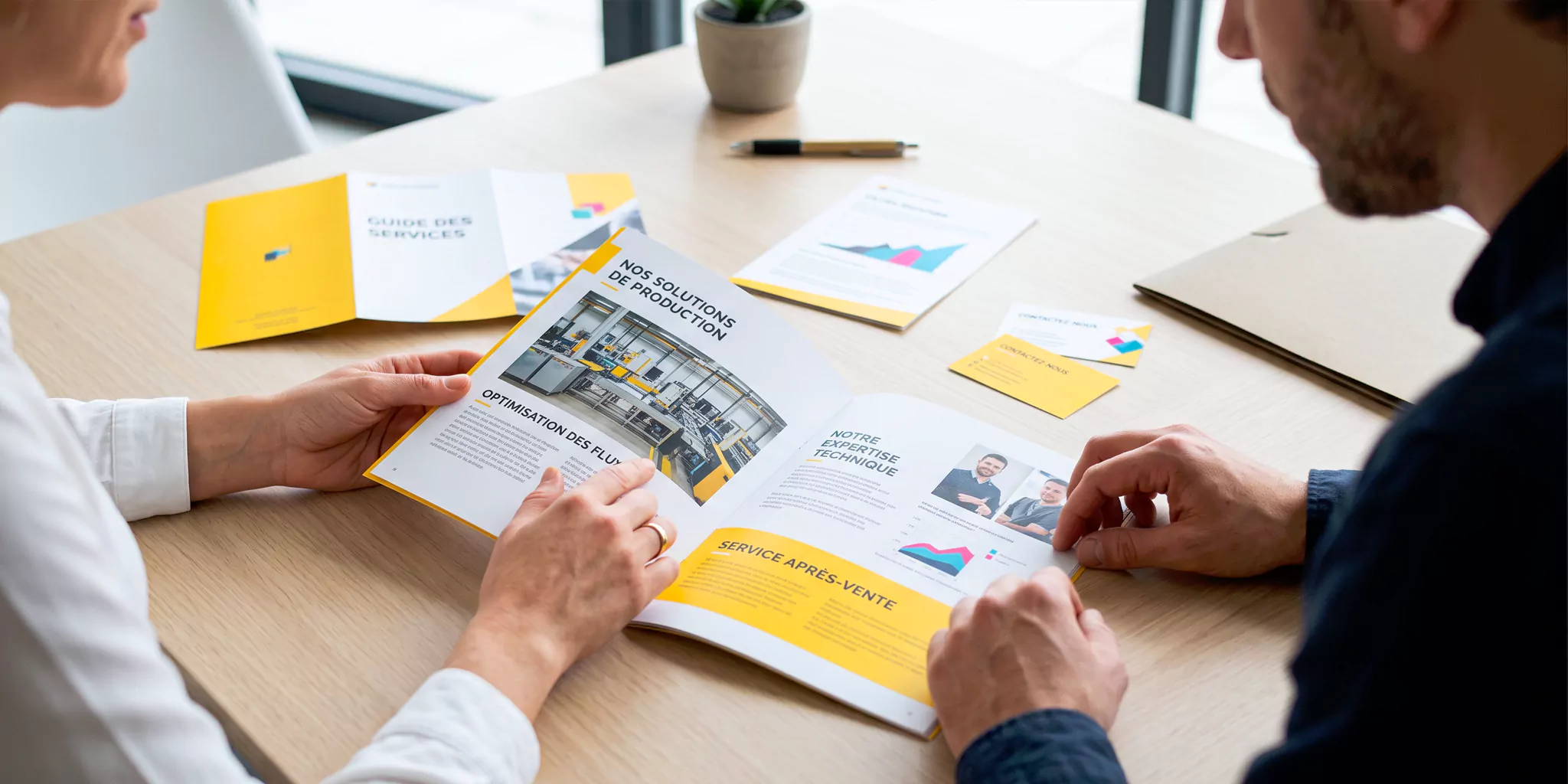 Deux professionnels consultant ensemble une plaquette industrielle lors d’un rendez-vous