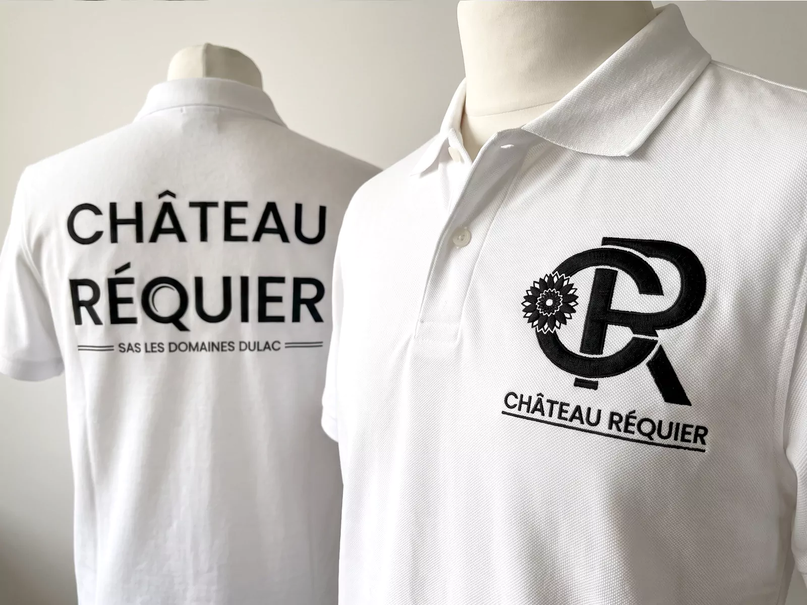 Application du logo Château Réquier en broderie noire sur la poitrine et au dos de polos blancs.