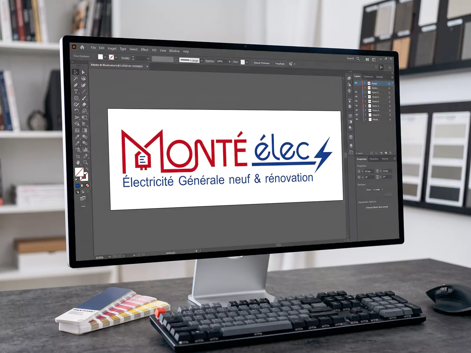 Logo rouge et bleu Monté élec affiché dans Illustrator sur un écran, avec un clavier, une souris et un nuancier sur le bureau.