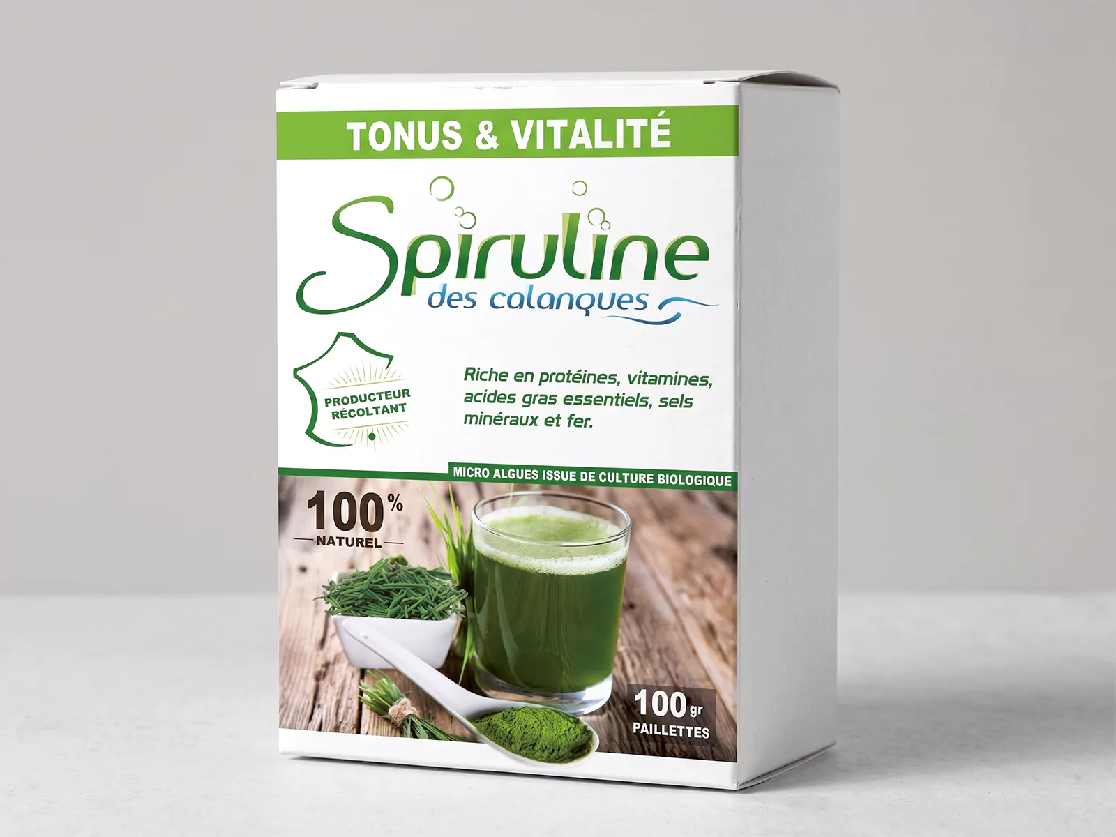 Mise en situation du visuel Spiruline des Calanques sur une boîte blanche, avec le logo vert et bleu et la présentation du produit en paillettes.